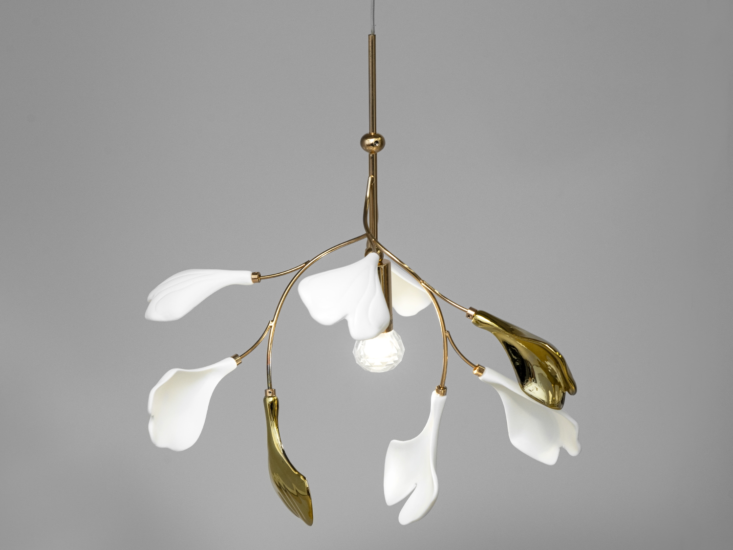 Люстри 2024 тренди. Вишукана фарфорова&nbsp;люстра арт деко являє собою шедевр дизайну, який знаходить гармонію між природною красою та сучасною естетикою. Міцний металевий каркас люстри слугує основою для ніжних керамічних пелюстків, що мають форму листя Гінкго Білоба &ndash; дерева, знаного своєю красою та лікувальними властивостями, яке було символом мудрості та довголіття ще з часів античності.
Пелюстки з фарфору-бісквіту, неглазуровані та білі, нагадують за текстурою мармур античних палаців, вони додадуть простору відчуття стабільності та історичної глибини. Їхній природний мотив втілює спокій та розслаблення, привносячи в інтер&rsquo;єр елементи природної гармонії.
Контрастуючи з цим, пелюстки з глазур'ю під металік у золотих або хромованих кольорах вносять сучасні акценти та розкішний блиск, що ідеально поєднується зі світлом лампи E14, створюючи в інтер'єрі неповторну атмосферу.
Регульована висота люстри із фарфору дає можливість змінювати розміщення світильника залежно від потреб простору, забезпечуючи оптимальне освітлення та створення затишку у вашому домі.&nbsp;
Даний фарфоровий світильник підвіс може бути вдало використаний в різних стилях інтер'єру, додаючи свою елегантність та вишуканість до кожного простору. Виділимо декілька основних стилів, де цей світильник може виглядати особливо впізнавано:
Класичний стиль:
В елегантних інтер'єрах з класичним декором та розкішшю, люстра підвіс у формі листя Гінкго Білоба додасть елементи старовинності та естетики. Глазуровані пелюстки можуть чудово гармоніювати зі збереженими меблями та деталями у стилі ренесансу або бароко.
Модерн:
В сучасних інтер'єрах, оформлених у мінімалістичному або модерному стилі, неглазуровані білі пелюстки привнесуть елемент природної простоти та гармонії. Металевий каркас і глазуровані пелюстки у золотих або хромованих відтінках додадуть сучасних акцентів.
Арт-деко:
Глазуровані пелюстки в золотих або хромованих відтінках ідеально впишуться в арт-деко інтер'єри, надаючи приміщенню розкішний блиск та різноманіття.
Еклектика:
У стилі еклектики, де об'єднуються різні елементи різних стилів, цей світильник може стати вдалим поєднанням класики та сучасності, створюючи унікальну атмосферу.
Лофт:
У лофт-інтер'єрах, де цінується індустріальний стиль та відкриті простори, натуральні пелюстки та металевий каркас додають природності та текстурність.
Цей світильник видається універсальним, спроможним доповнити різноманітні стилі інтер'єру, вносячи у них вишуканість та особливий характер.
Наш світильник-підвіс можна успішно використовувати в різних типах приміщень, додаючи свою унікальну естетику та освітлення. Розглянемо його застосування в конкретних видах приміщень:
Їдальня або Ресторан:
Завдяки своєму стильному та елегантному дизайну, світильник ідеально підійде для створення атмосферного освітлення в ресторанах чи їдальнях, де можна підкреслити елегантність та стиль інтер'єру.
Сучасний Офіс або Робочий Кабінет:
В сучасних офісах чи робочих кабінетах цей світильник арт деко може додати не лише необхідне освітлення, але й створити стильну атмосферу та відзначити професійний підхід.
Лобі Готелю чи Лобі Компанії:
Як центральний елемент при вході в готель чи офіс, світильник арт деко може вразити своєю вишуканістю та створити гармонійну атмосферу для вітання гостей чи клієнтів.
Житлова Кімната або Вітальня:
В житлових приміщеннях цей світильник може стати ефектним доповненням до вітальні, додаючи в неї вишуканість та затишок.
Арт-галерея або Музей:
У місцях, де важлива естетика та витонченість, таких як арт-галереї чи музеї, цей світильник може витончено доповнити інтер'єр та освітлити твори мистецтва.
Лофт чи Сучасне Студійне Приміщення:
У лофт-інтер'єрах чи студійних просторах цей світильник додасть текстурність та природність, створюючи унікальну атмосферу та витончений вигляд.
Таким чином, цей фарфоровий світильник виявиться вдалим рішенням для освітлення та декорування різноманітних приміщень залежно від їхнього призначення та стилю.
Наш фарфоровий світильник-підвіс з пелюстками у формі листя Гінкго Білоба стане центральним елементом оформлення приміщення, додавши до нього стиль, елегантність та трохи природної магії.
Чудовим дизайнерським рішенням, було б придбання всього комплекту із серії &laquo;Гінкго Білоба&raquo;. До нього входять: фарфорові люстри круглої форми, фарфорові люстри витягнутої форми, фарфорове бра, фарфоровий торшер, фарфорові настільнні світильники.
Ключові слова: купити люстру у вітальню недорого, стиль тіффані, сучасні люстри на кухню, лампа юа, декоративні люстри з фарфорукупити люстру.
Лампа в комплект не входить.